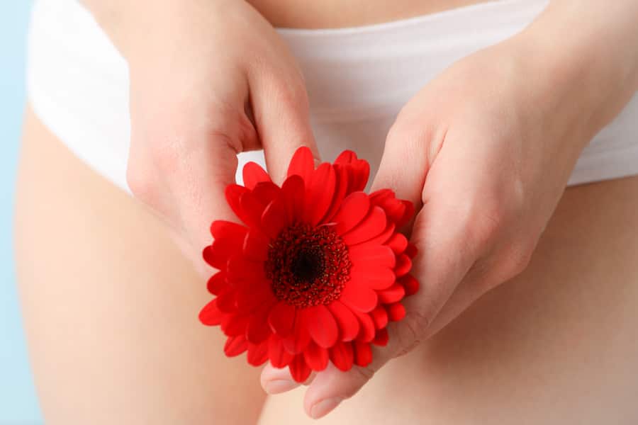 A woman holding a flower as a gentle symbol of intimate care